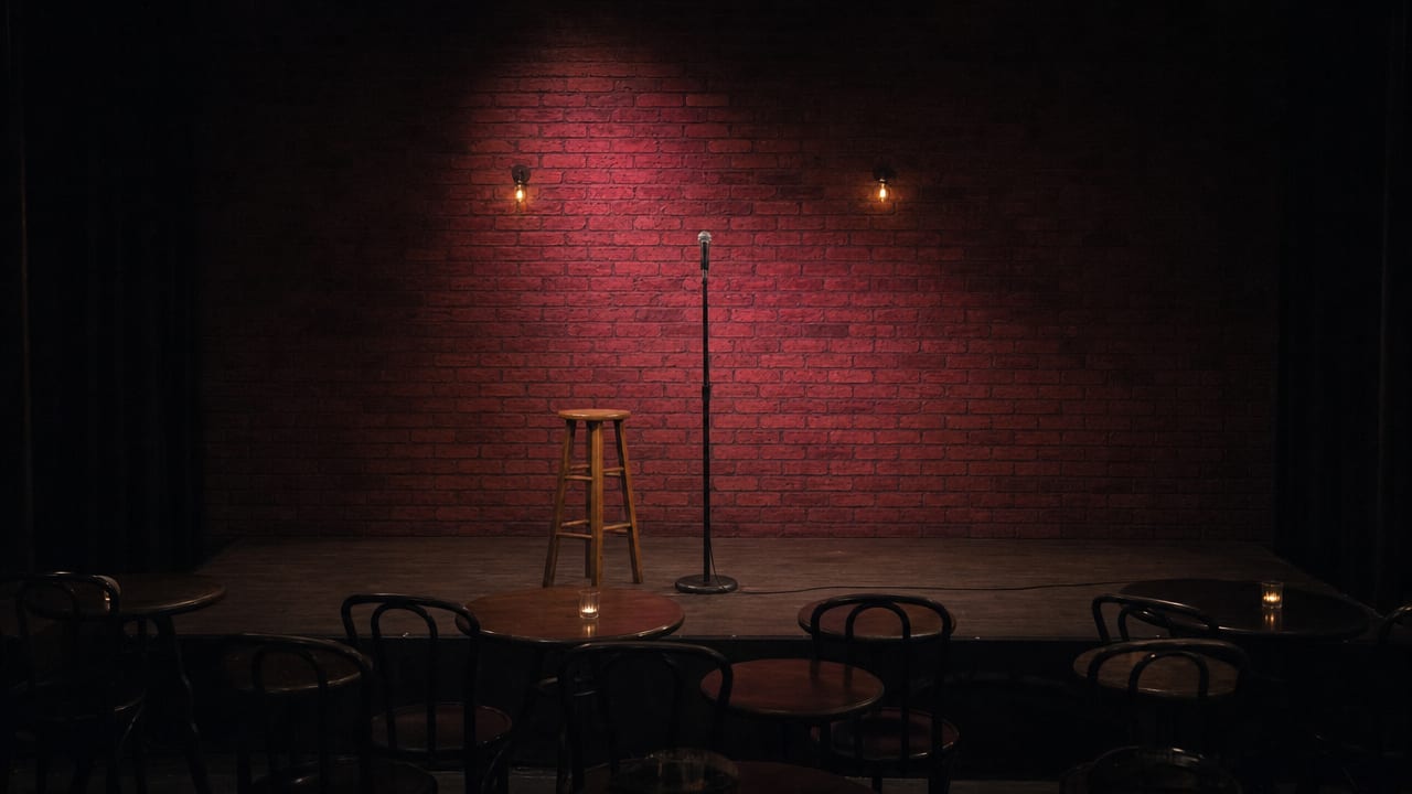 An empty comedy room with stacked chairs and one mic stand